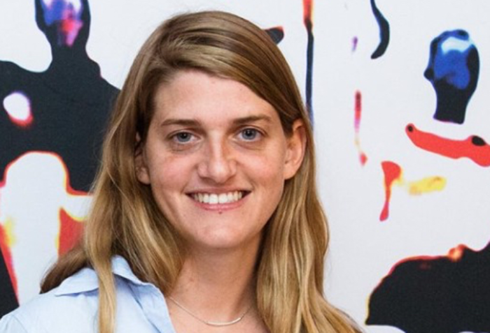 A headshot of Marjolaine Grappe in front of a multi-colored, swirling background.